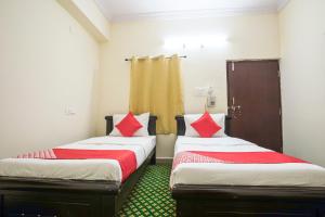 two beds in a room with red and white pillows at OYO Flagship13162 Swiss Legrand in Hyderabad
