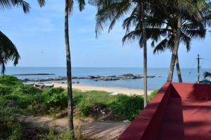 uma vista para a praia a partir de um resort com palmeiras em Abraham Beach House em Cananor