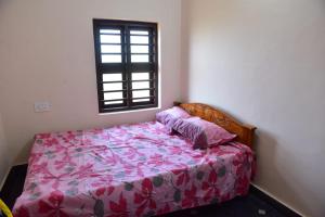 um quarto com uma cama com um edredão rosa e uma janela em Abraham Beach House em Cananor