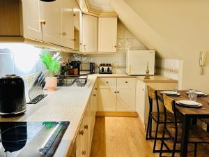 a kitchen with white cabinets and a table with chairs at Wimbledon Elegance: 2-bedroom Retreat in London
