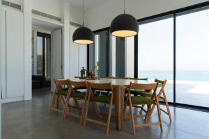 a dining room with a table and chairs and large windows at Zita Fidar in Al Fīdār