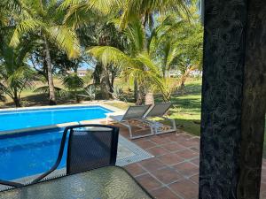 Golf Views Near Bayahibe & Casa De Campo في لا رومانا: اطلاله على مسبح مع كرسيين والنخيل