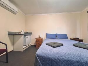 a bedroom with a bed with blue sheets and a counter at Exchange Hotel Greenbushes in Greenbushes
