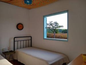 1 dormitorio con 1 cama y una ventana con un árbol en Casinha Original de Fazenda, en Araras