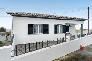 a white house with black windows and a fence at Casa das Hortênsias in Raminho