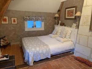um quarto com uma cama com lençóis brancos e uma janela em Le Clos Mademoiselle em Loches