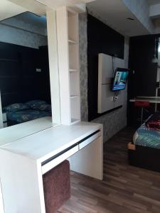een kamer met een bureau, een tv en een bed bij Inapin Aja by Dio Property in Bandung