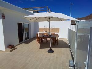 a white umbrella on a patio with a table and chairs at La Catumbela in Tuineje