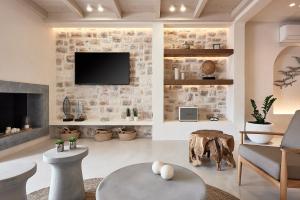 a living room with a fireplace and a tv on a stone wall at The Sand Villas - 5star Living on the Beach in Agios Nikolaos