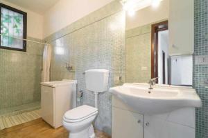 a bathroom with a white toilet and a sink at Villa Greta By Vivimy in Parabita +20 photos