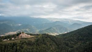 una casa en una colina con montañas en el fondo en Abbatissa Hotel Restaurant en Sant Joan de les Abadesses