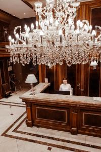 a man sitting at a desk under a chandelier at Time Hotel&SPA in Chişinău