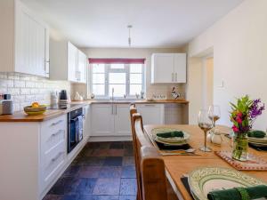 cocina con armarios blancos y mesa de madera en 2 bed in Braunton 83730 en Barnstaple