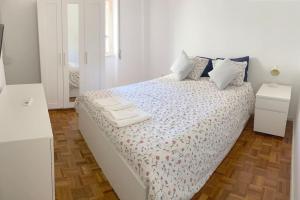 ein weißes Schlafzimmer mit einem Bett mit zwei Handtüchern darauf in der Unterkunft Estoril 2 bedrooms by the Beach in Estoril