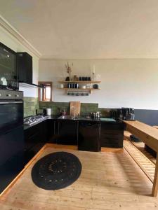 duża kuchnia z czarnymi urządzeniami i drewnianą podłogą w obiekcie Edwardian Villa by the sea-side w mieście Walton-on-the-Naze