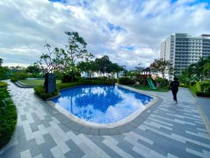 une personne se promenant au bord d'une piscine dans un parc dans l'établissement Frost at Air Residences Makati, à Manille