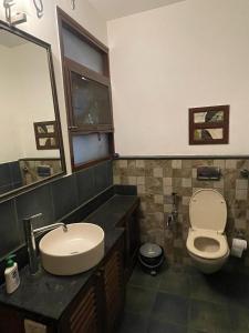 a bathroom with a sink and a toilet and a mirror at Jugglers Rest - The Grand Suite in Bangalore