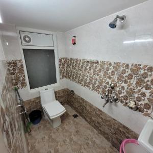 Un pequeño baño con inodoro y ventana. en Vazeer Residency, en Hyderabad