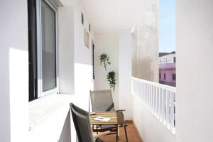einen Balkon mit einem Stuhl, einem Tisch und einem Fenster in der Unterkunft Apartamentos Las Majoreras 1 y 2 dormitorios in Las Majoreras