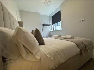 a white bedroom with a bed with pillows and a window at Superior Stay, Sophia Gardens, City Centre and Stadium Sleeps 4 in Cardiff