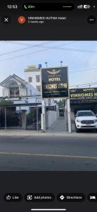 una señal para un hotel con un coche aparcado en la calle en Khách Sạn Vinhomes Huỳnh Hotel en Ben Tre