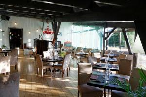 a restaurant with tables and chairs in a room at Hotel du Lac & Restaurant Foix in Foix