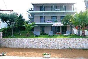 budynek z krzesłami i parasolem przed nim w obiekcie xanthi's sea front villas w mieście Flámbouras