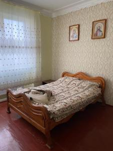 - une chambre avec un lit en bois devant une fenêtre dans l'établissement Apartment Bograch, à Moukatcheve