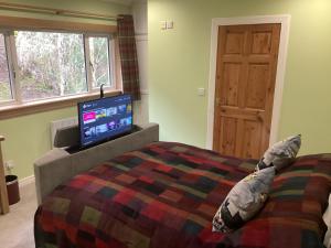 a bedroom with a bed with a flat screen tv at Taigh Sealladh Fèidh B&B in Fort Augustus