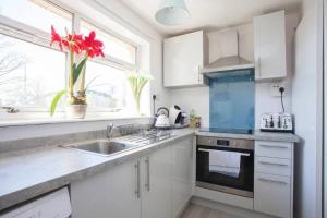 a kitchen with white cabinets and a sink and a window at Cosy 1 Bed with Parking in City Centre in Glasgow