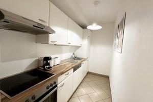 a small kitchen with white cabinets and a sink at Cosy & New Urban Apartment in Green Hood in Vienna