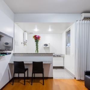 una cocina blanca con 2 sillas y una barra en Max Savassi Apart Service en Belo Horizonte