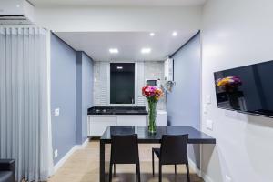 uma sala de jantar com um vaso de flores sobre uma mesa em Max Savassi Apart Service em Belo Horizonte