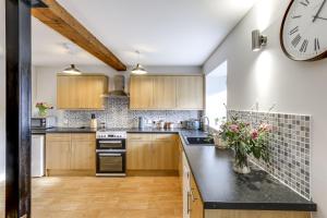 una cocina con armarios de madera y un reloj en la pared en The Old Warehouse Ely "Apartments", en Ely