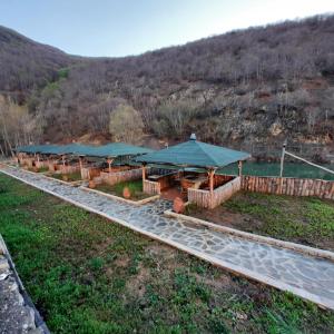 una fila de mesas con sombrillas verdes en un campo en Yeşilgöl doğa evleri, en Tokat