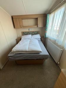 1 dormitorio con 1 cama con sábanas blancas y ventana en Bittern 13, Scratby - California Cliffs, Parkdean, sleeps 6, pet friendly, bed linen and towels included - close to the beach en Great Yarmouth