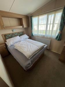 Cama en habitación pequeña con ventana en Bittern 13, Scratby - California Cliffs, Parkdean, sleeps 6, pet friendly, bed linen and towels included - close to the beach en Great Yarmouth