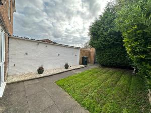 a yard with a white garage with two potted plants at Contemporary-styled 3-Bed House in Buckinghamshire