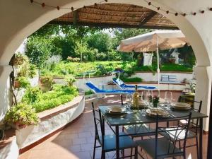 - une table avec des chaises et un parasol sur la terrasse dans l'établissement Villa i Ginepri. A pochi passi dal mare., à Marina di Sorso