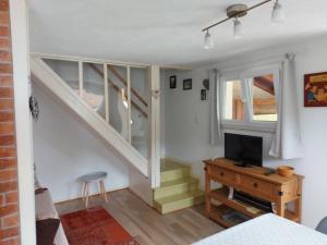 sala de estar con escalera y TV en La petite maison Gîte 2 étoiles, en La Bresse