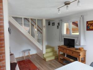 a living room with a staircase and a television at La petite maison Gîte 2 étoiles in La Bresse