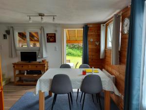 a dining room with a table and chairs and a television at La petite maison Gîte 2 étoiles in La Bresse