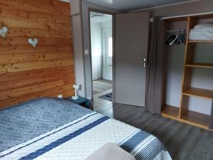 1 dormitorio con 1 cama y pared de madera en La petite maison Gîte 2 étoiles en La Bresse