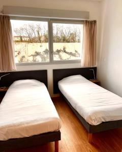 two beds in a room with a window at Résidence Hôtelière Le Prado in Libourne