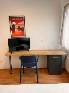 a wooden desk with a chair and a monitor at Résidence Hôtelière Le Prado in Libourne