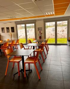 un comedor con mesas, sillas y ventanas en Résidence Hôtelière Le Prado, en Libourne