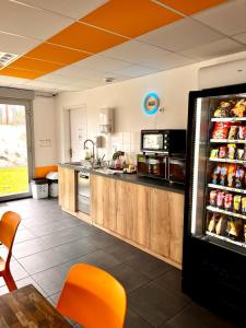 a large kitchen with a counter and a refrigerator at Résidence Hôtelière Le Prado in Libourne