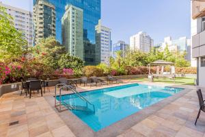 una piscina con sillas, mesas y edificios en Max Savassi Apart Service, en Belo Horizonte