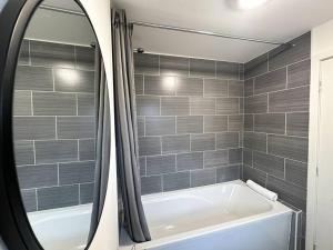 La salle de bains est pourvue d'une baignoire et d'un miroir. dans l'établissement Maddren House By Blue Skies Stays, à Middlesbrough