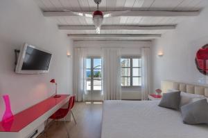 a bedroom with a bed and a tv on the wall at Fortan 5* villa in Mýkonos City